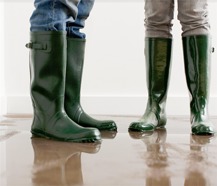 two people standing in a flooded room in rainboots